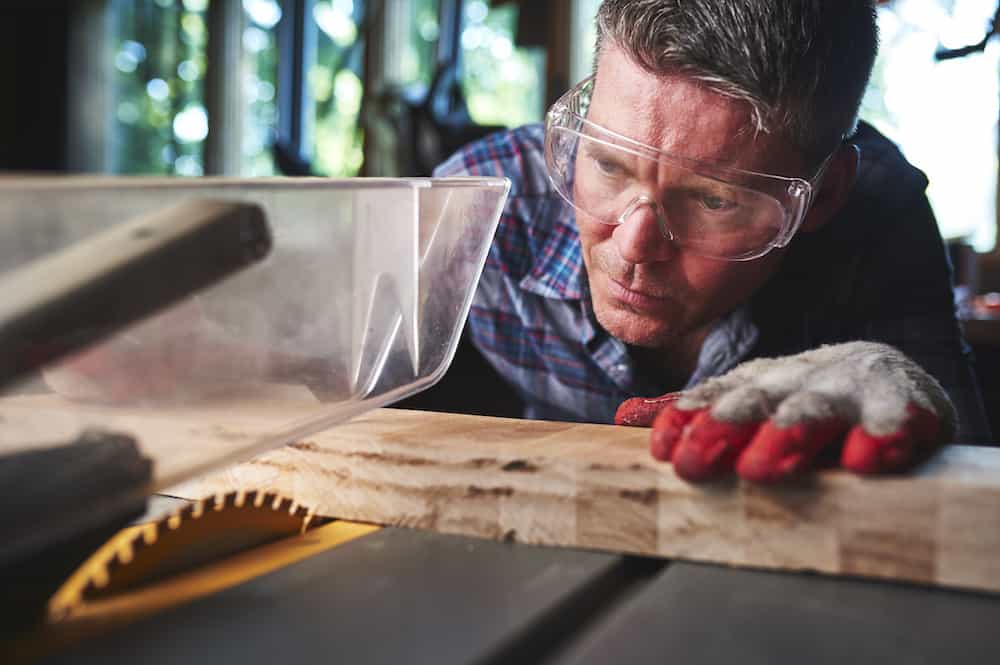 a man making a precise cut on a table saw difference between compound saw vs table saw