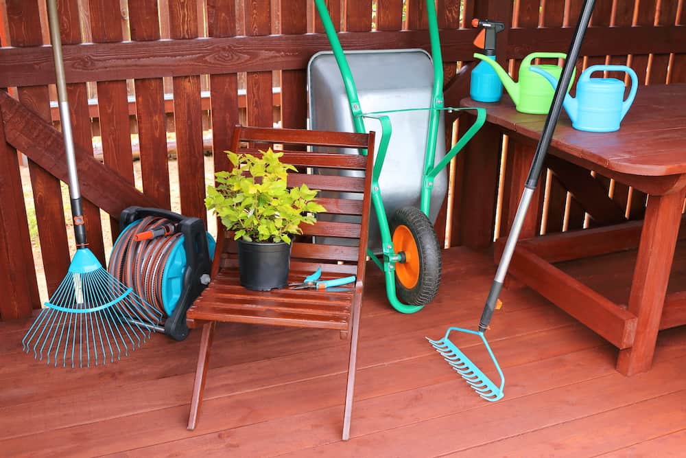 Decorative shrub along with garden equipment and tools in a wooden shed. tips on how to store garden hose